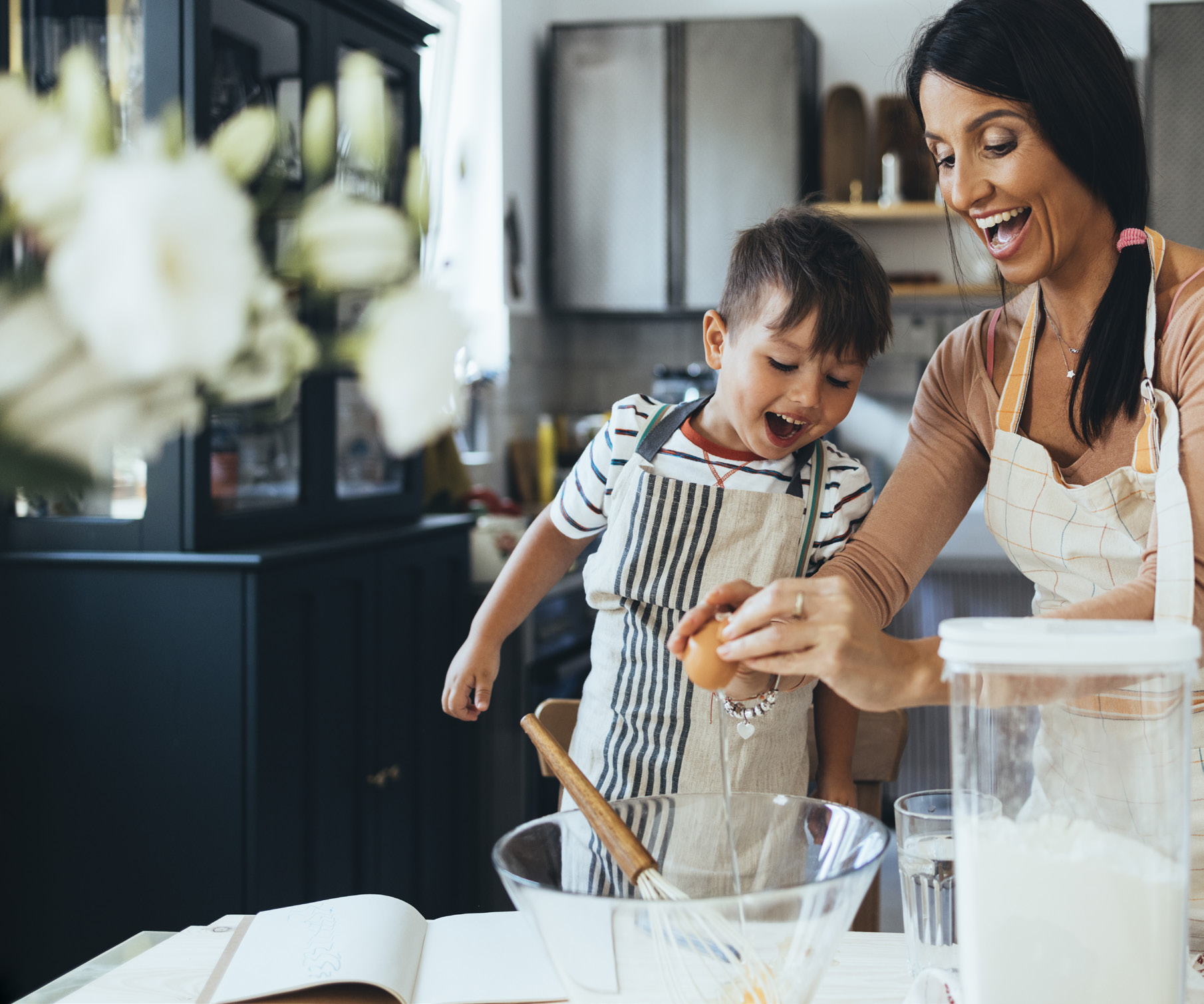 woman and young boy cracking an egg over a bowl