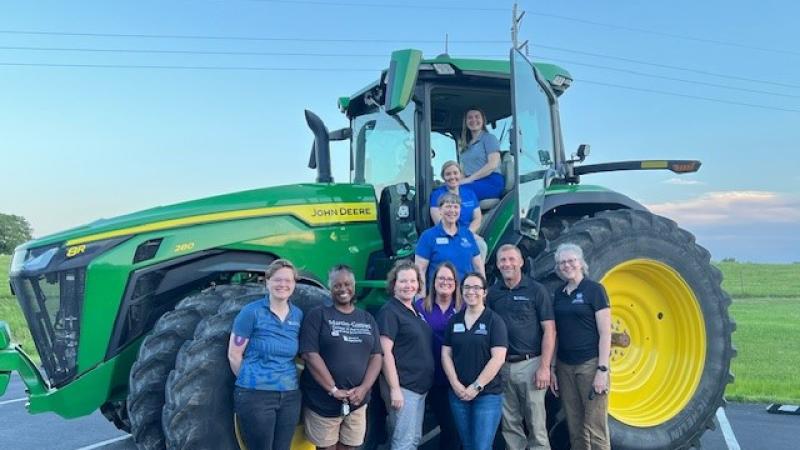 a group of people standing in front of a tractor