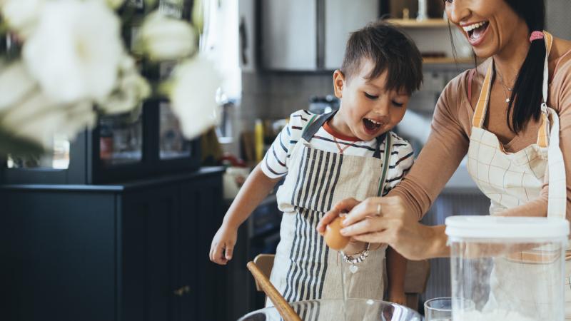 woman and young boy cracking an egg over a bowl